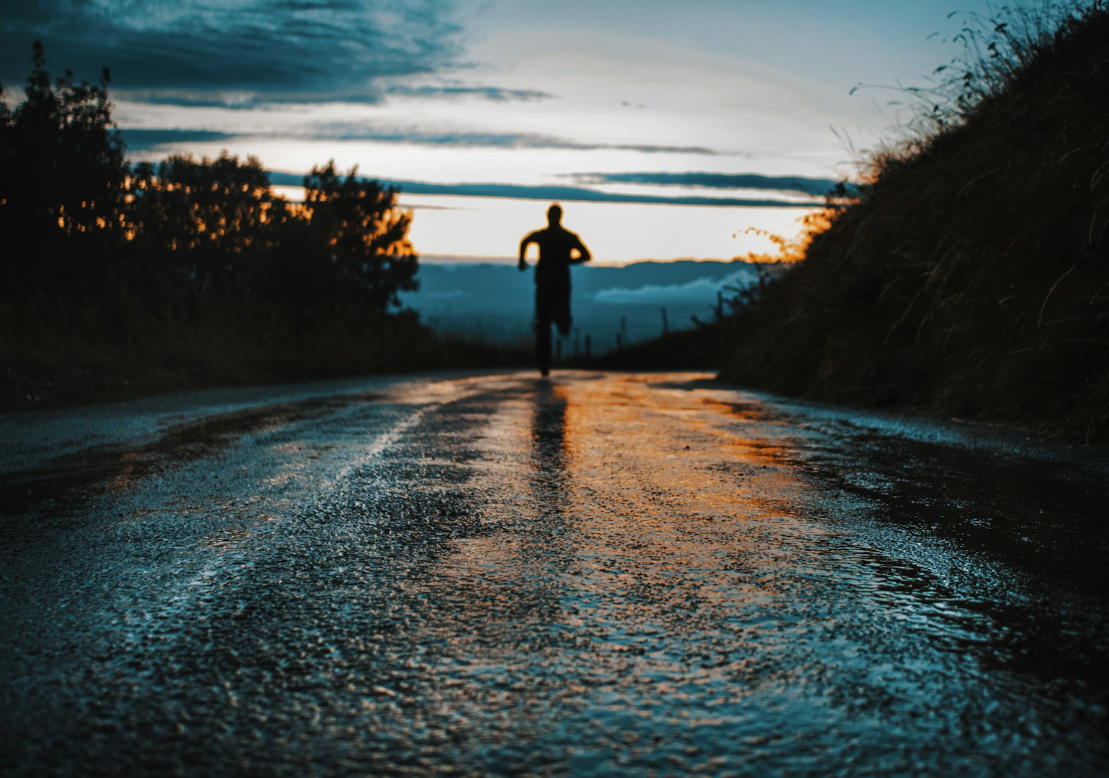 Silhouette of a person running on an open road at sunrise