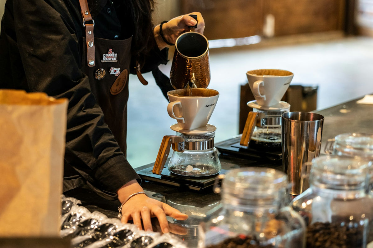 A barista gently pouring coffee into a cup