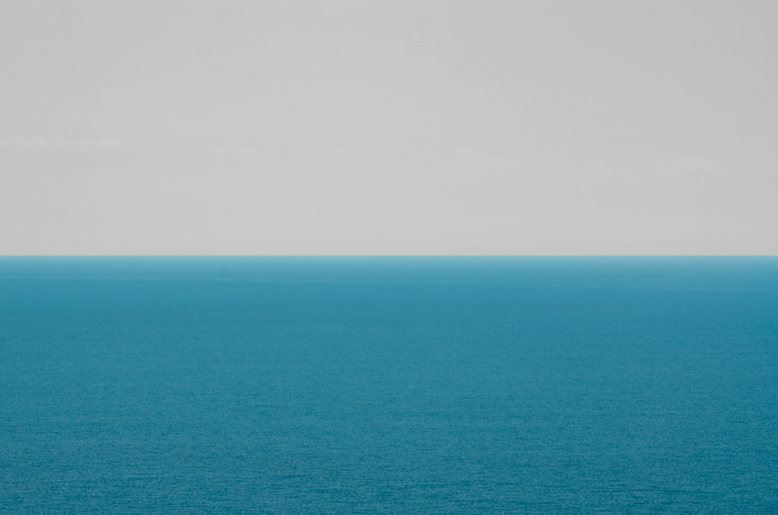 A large body of water stretching out beneath a wide, cloudy sky