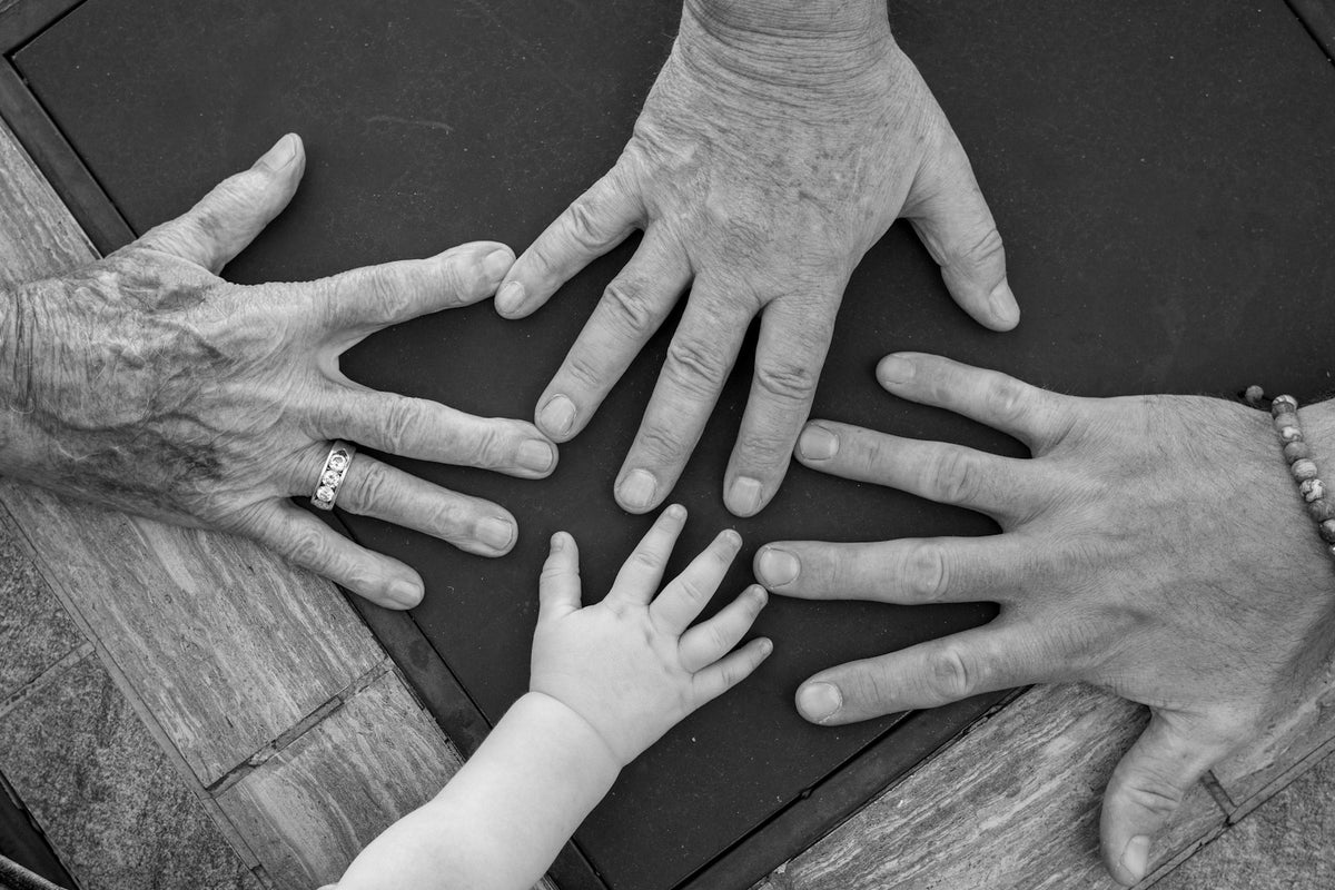 Four hands of different ages reaching towards the centre