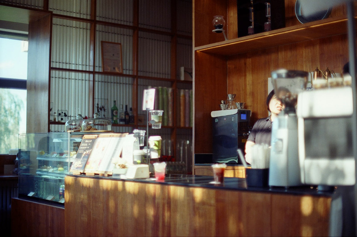 Barista behind a coffee counter with drinks and pastries