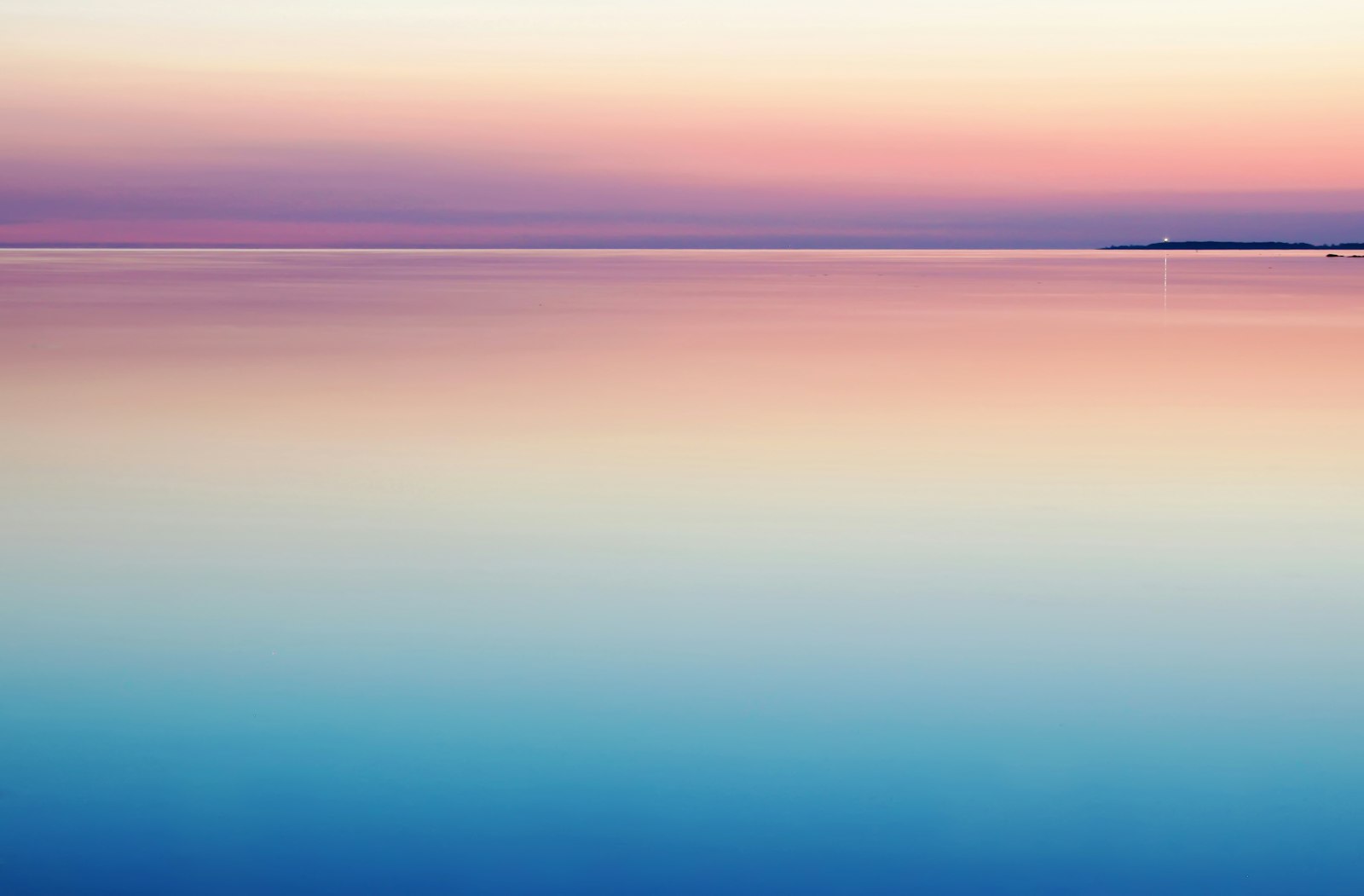 A calm sea at dawn beneath a pink and blue sky