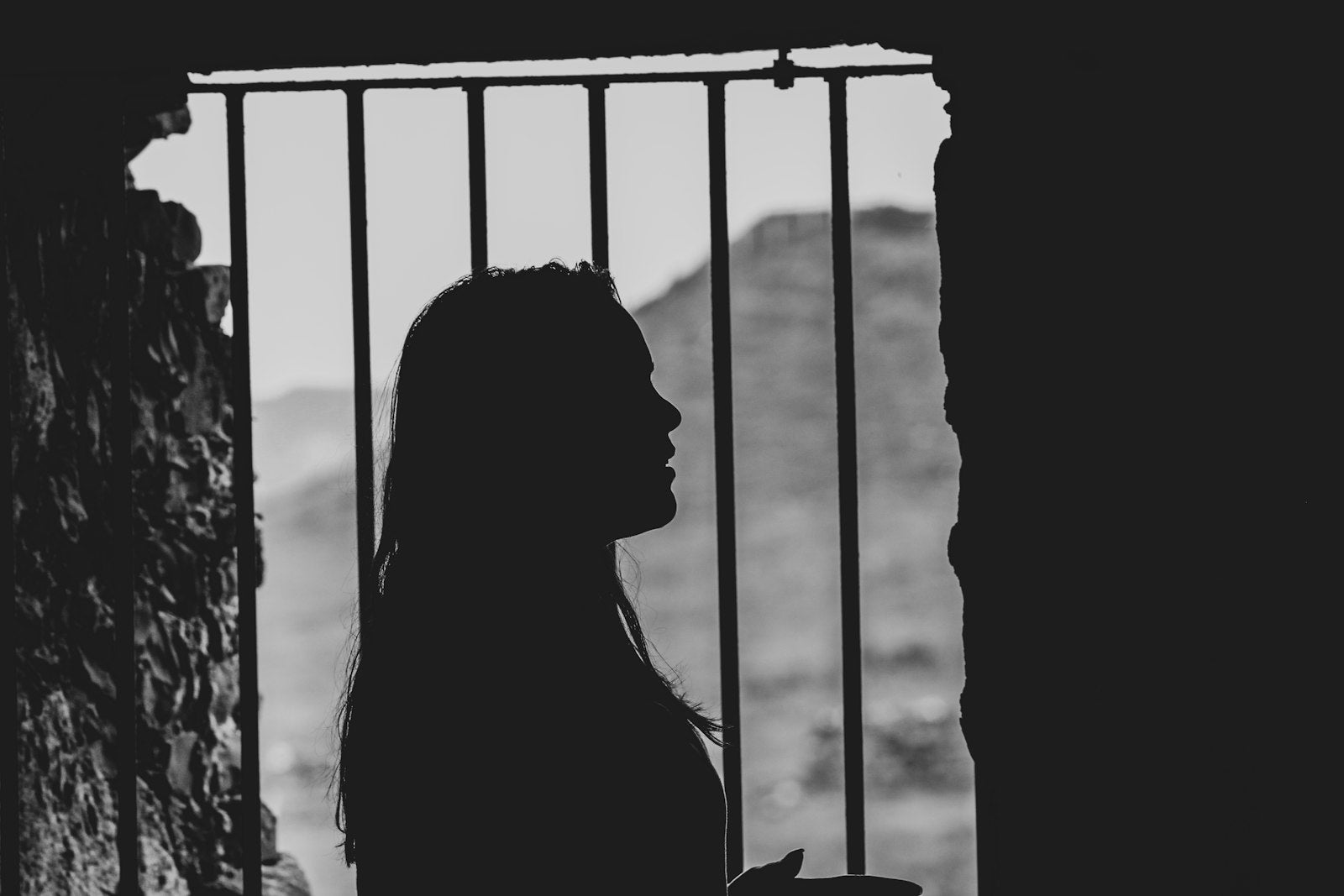 The shadow of a woman silhouetted against a barred window