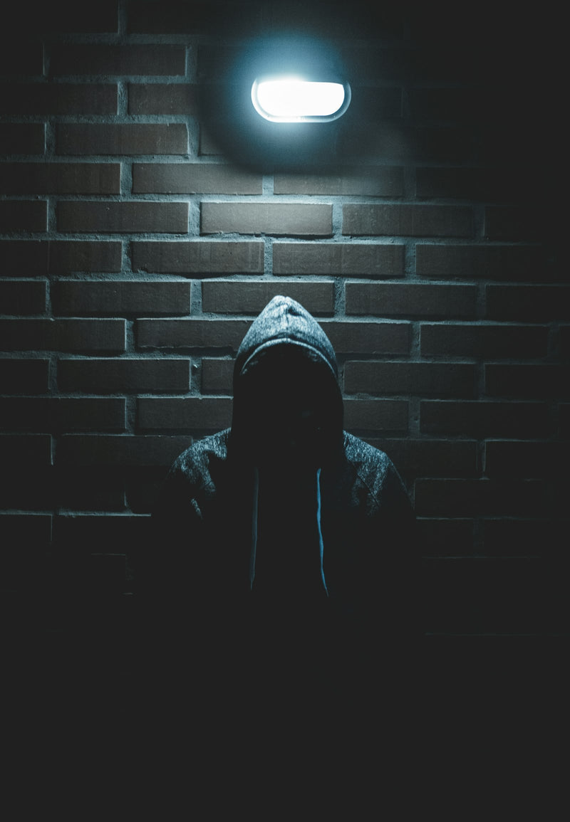 A hooded figure in a shadowed alley