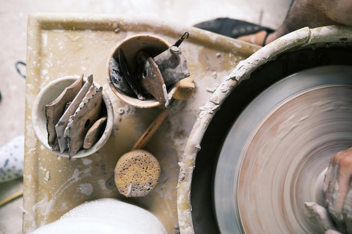 A person shaping clay on a spinning pottery wheel