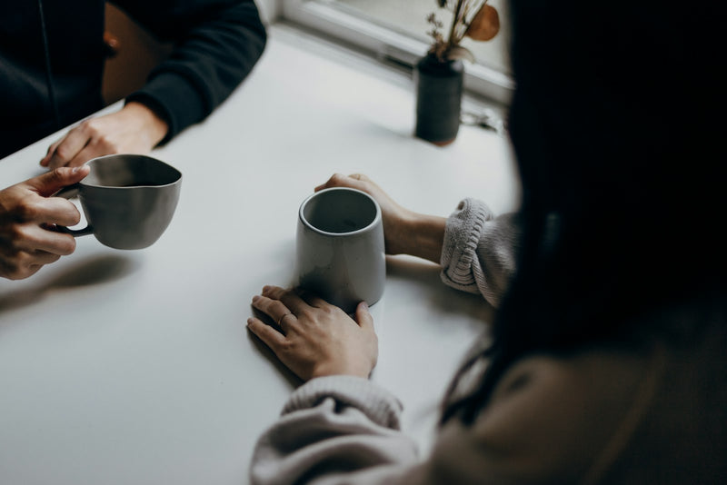 Two people holding coffee mugs, deep in unhurried conversation