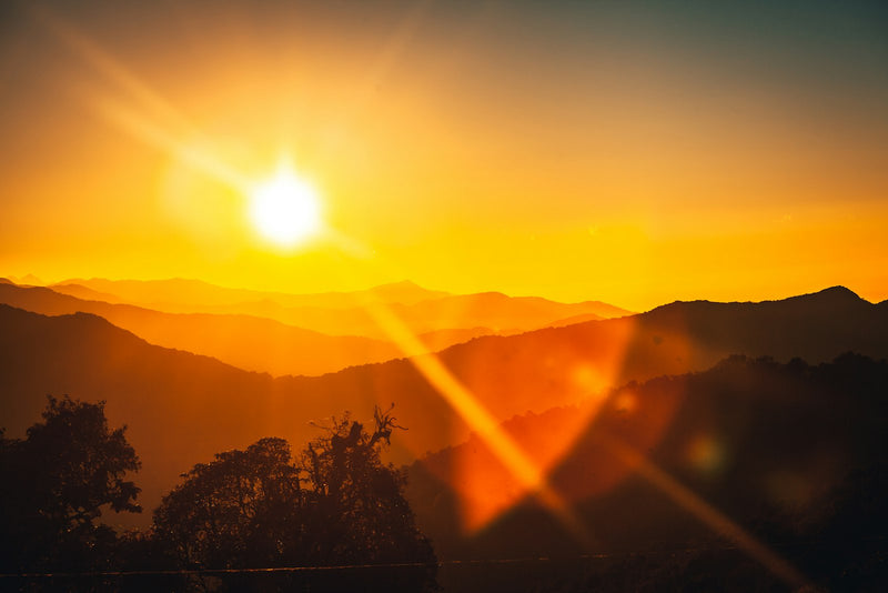 Sunrise breaking over a mountain ridge, warm light spreading across the sky