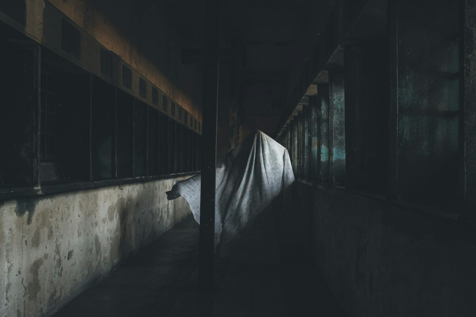 A dark, sparse room with a sheet on the wall