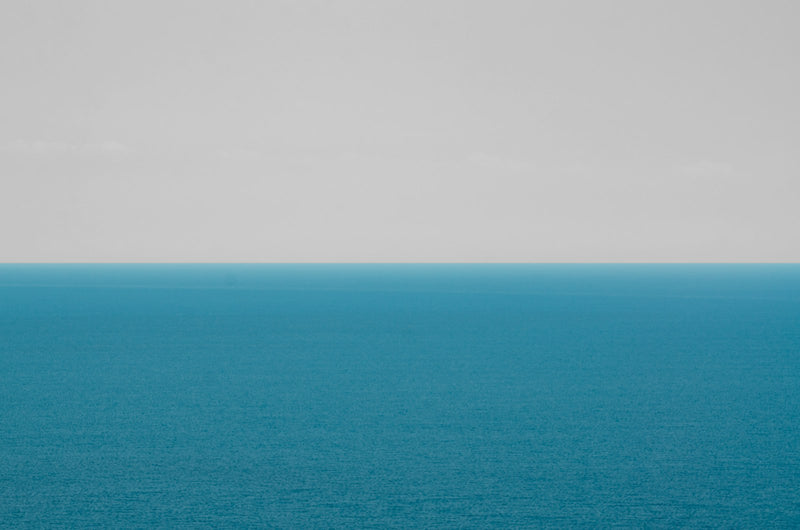 A large body of water stretching out beneath a wide, cloudy sky