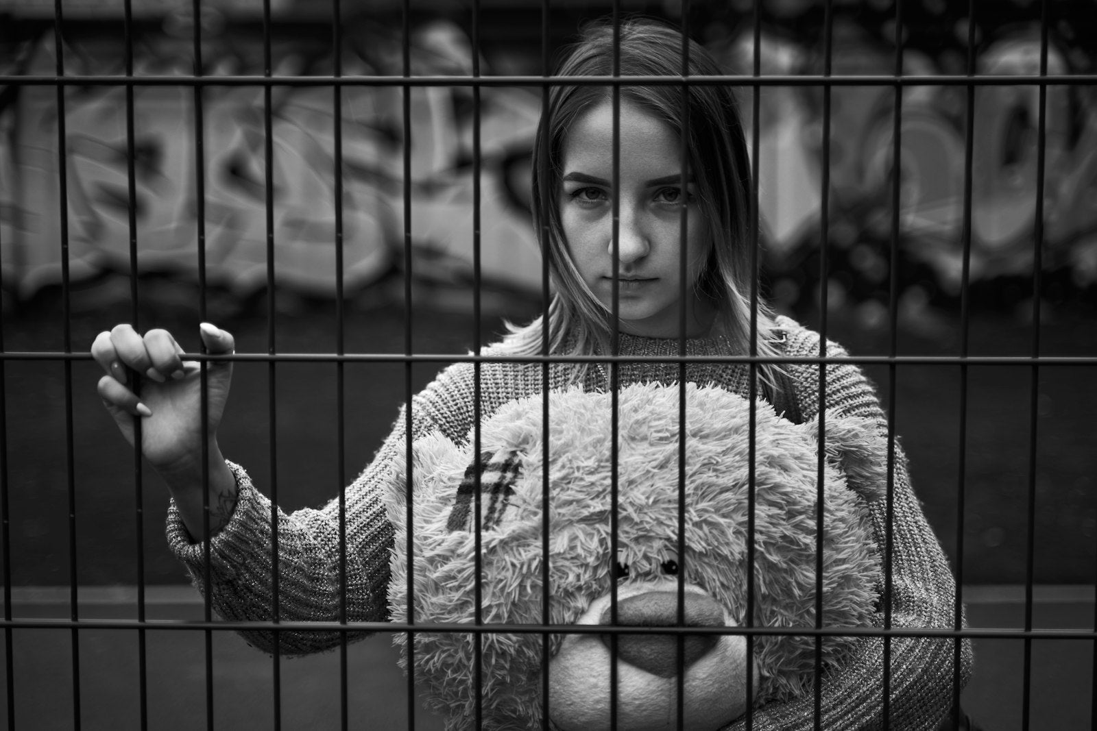 A lone young woman with long hair behind bars