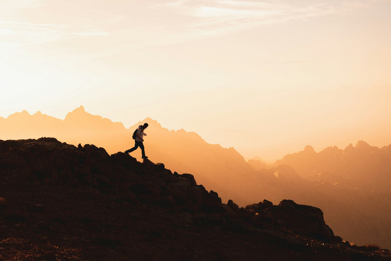 A lone figure standing on a mountain summit at first light