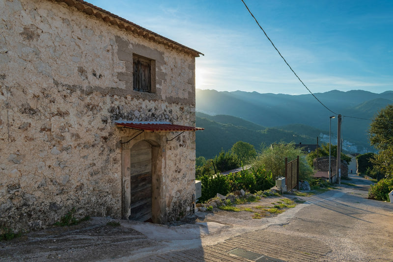 Old stone building on a hillside, lit by the low light of sunset