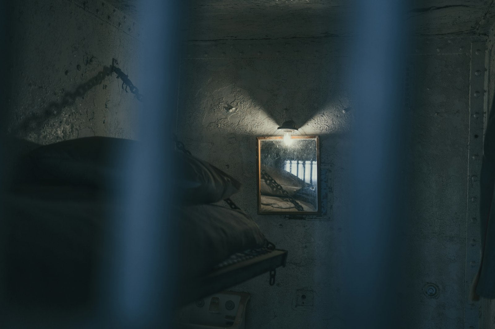 A dimly lit prison cell with a bed and a barred window
